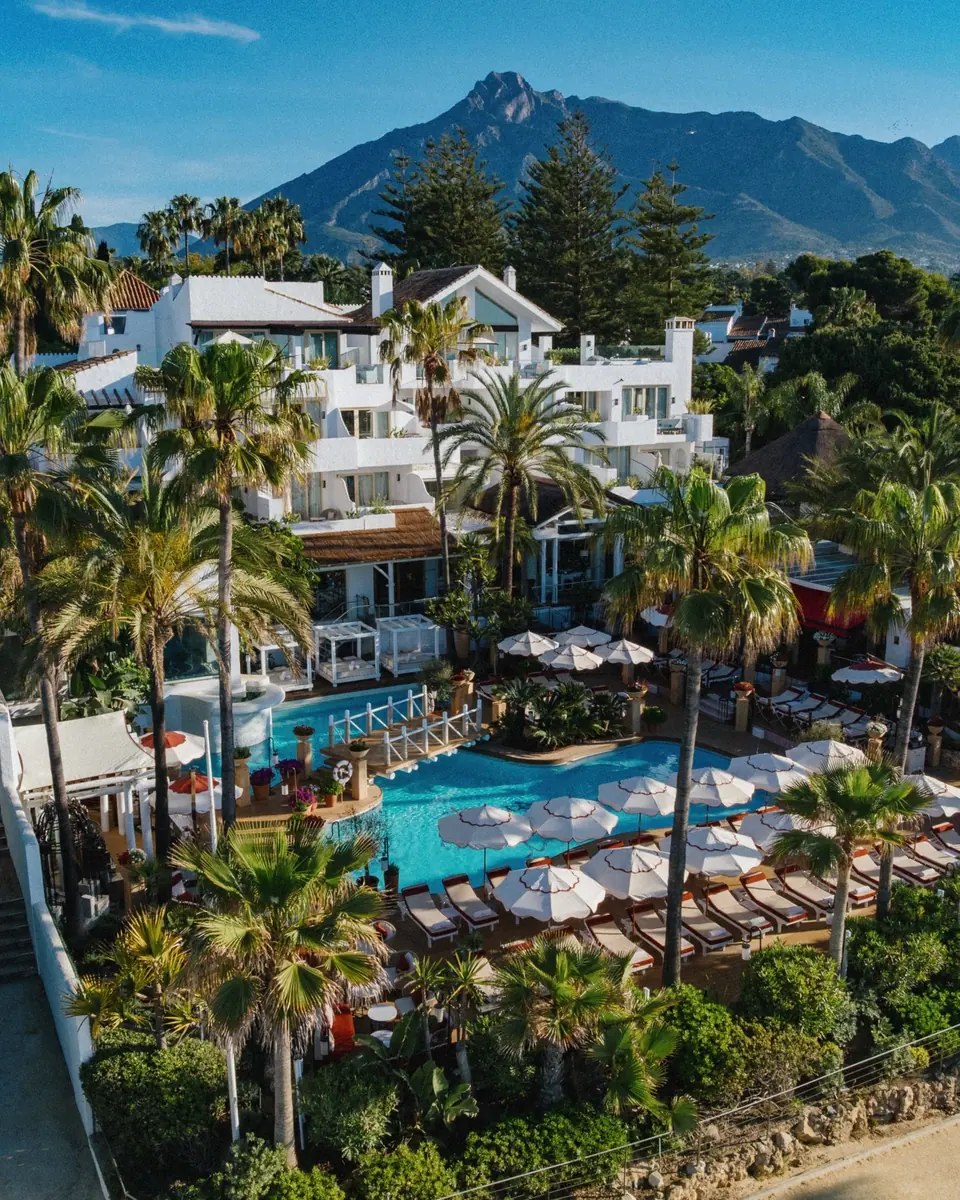 Aerial view of Puente Romano’s white buildings and gardens below La Concha mountain