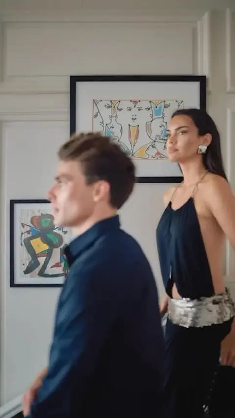 A couple beside framed artworks in a white room