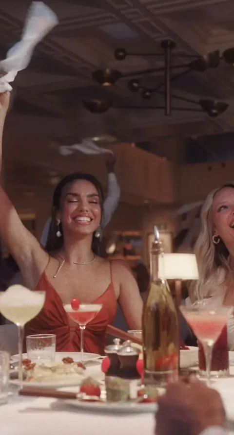 A guest waving a napkin at a lively dinner