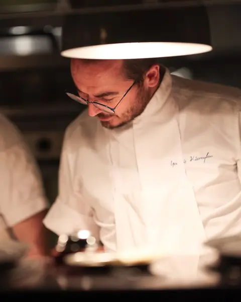 Chef Yiannis Kioroglou at the pass under the kitchen lights