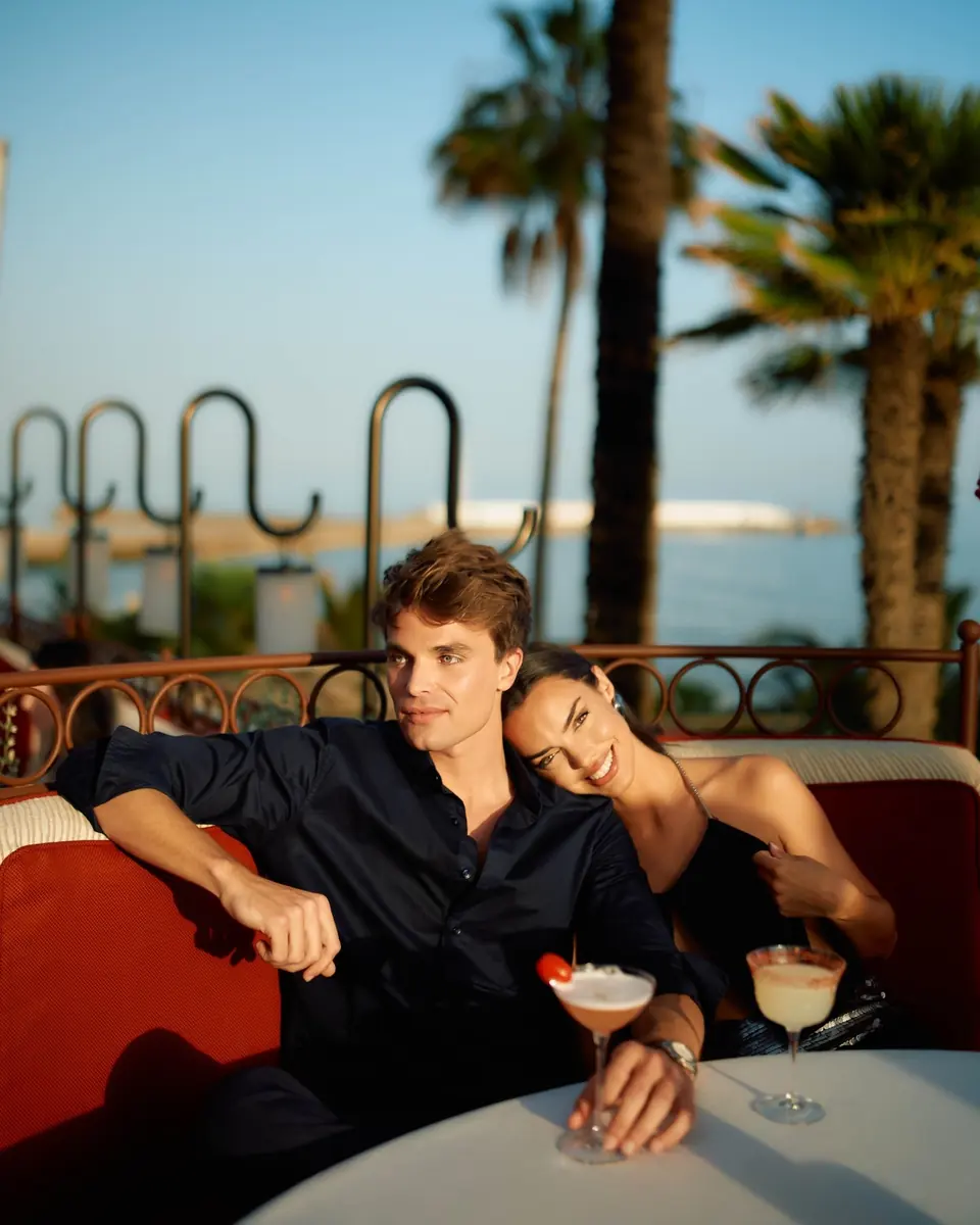 A couple on a red banquette on the terrace at golden hour