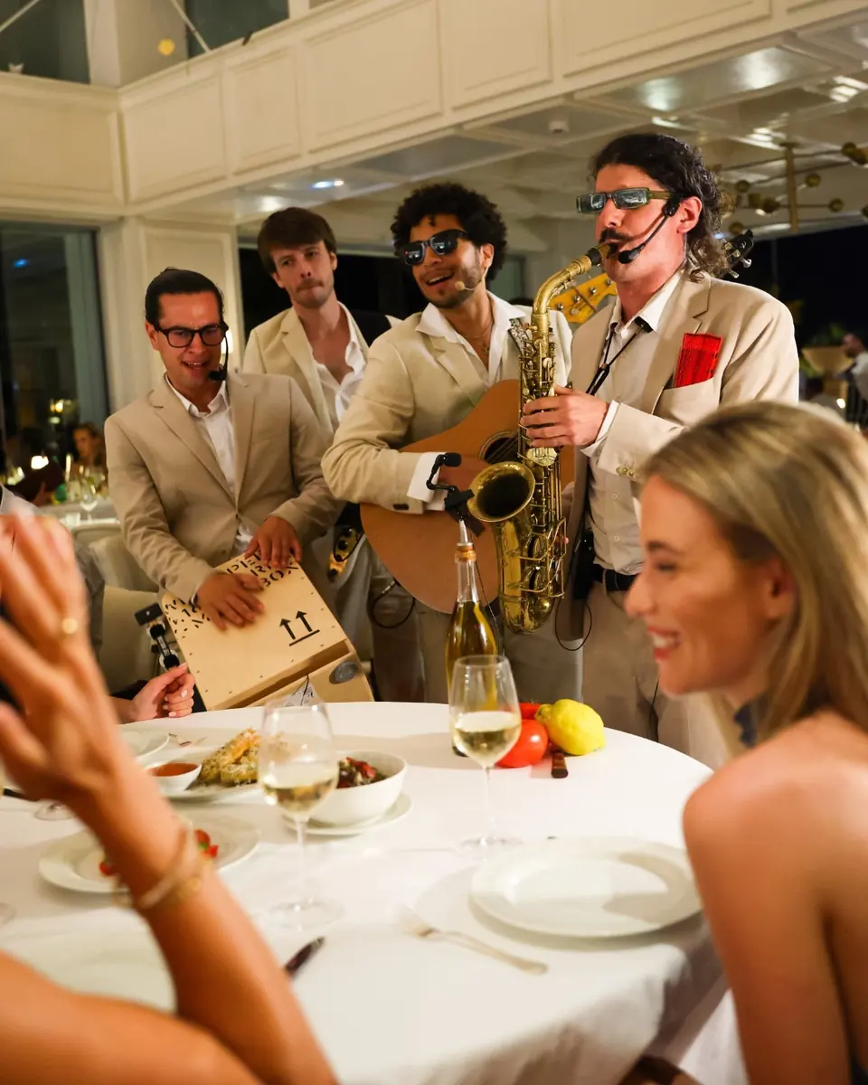 Musicians with guitar and saxophone playing between tables in the dining room