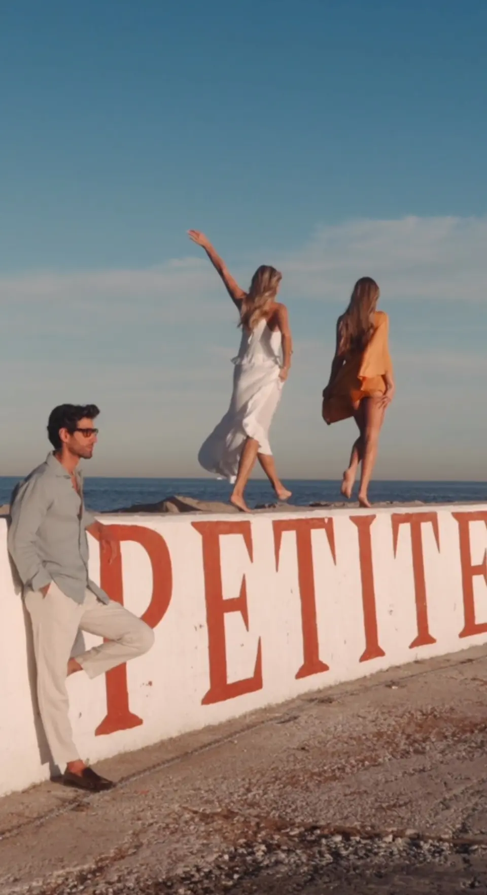 Guests dancing on the sea wall painted PETITE at sunset