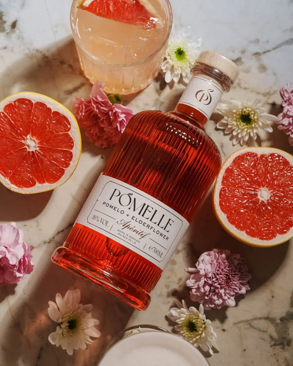 A bottle of Pomelle with grapefruit halves, flowers and a spritz