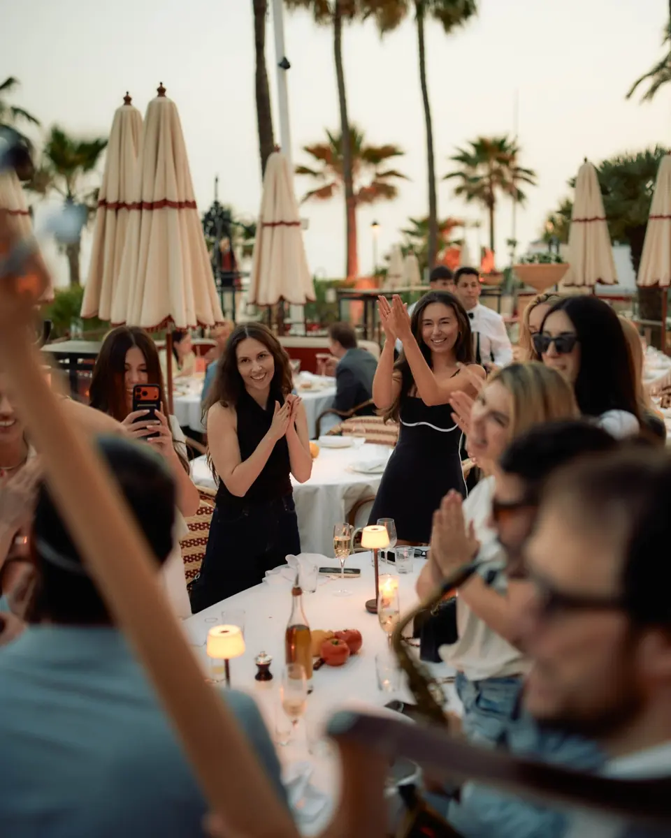 A full terrace applauding a live musician at sunset