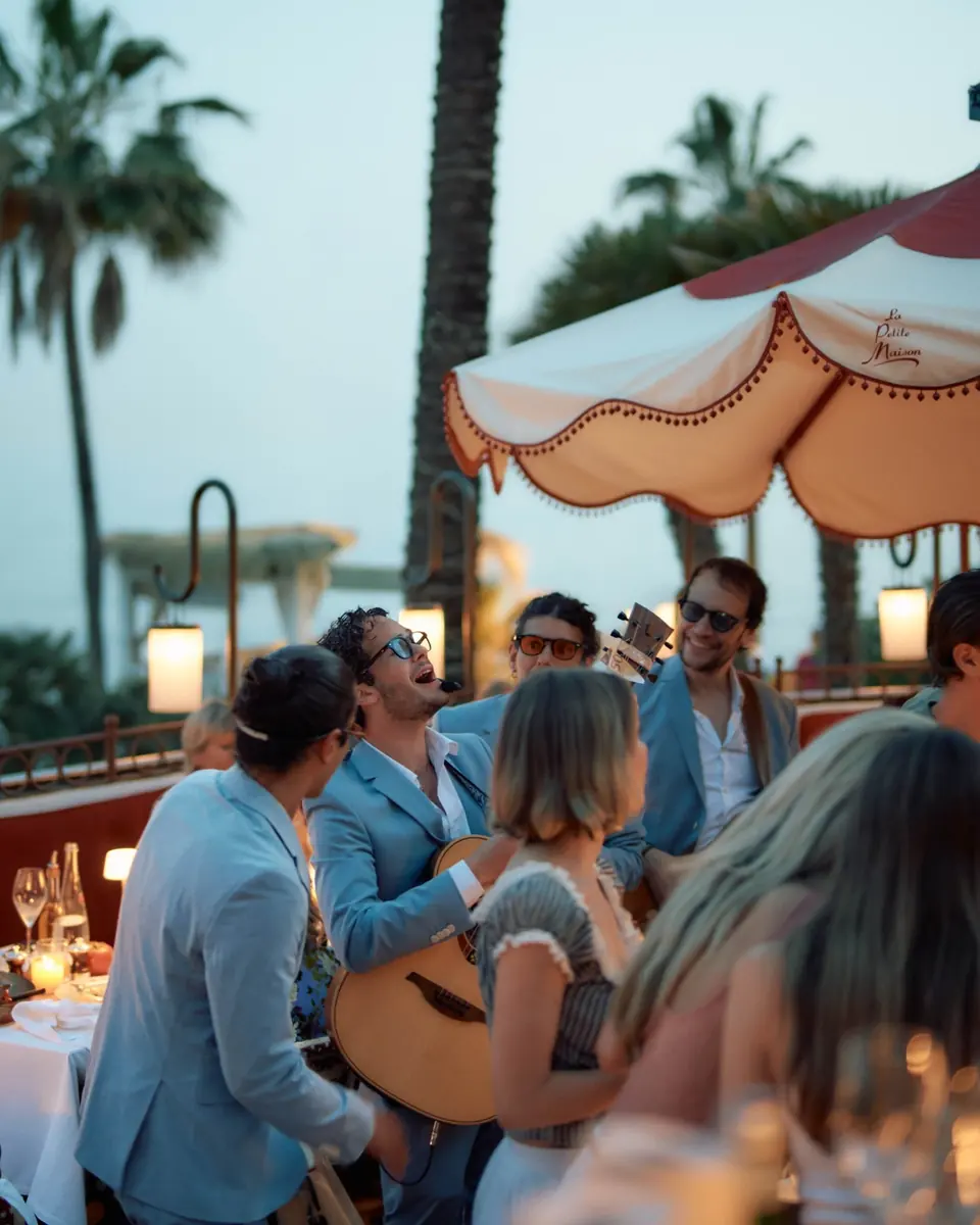 Guests singing with a guitarist on the terrace at dusk